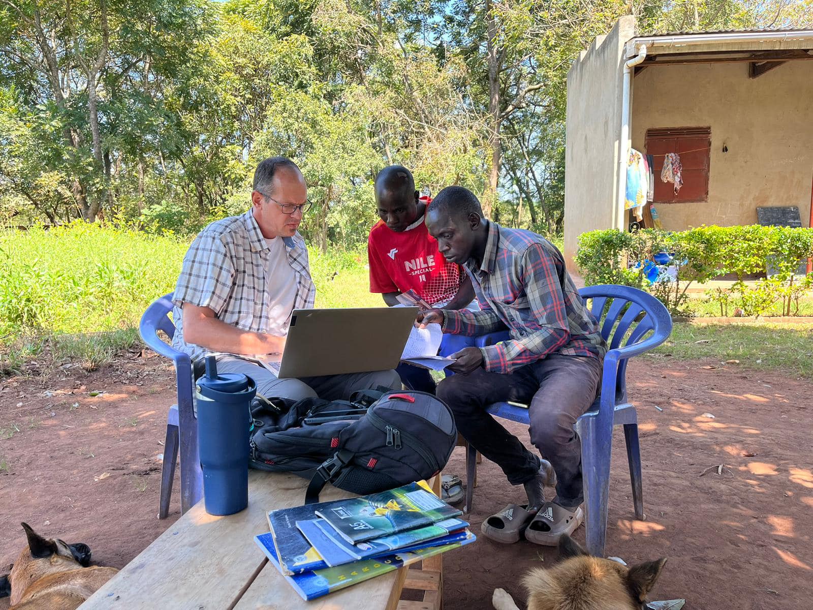 GJ mentoring students about finances Man seated with a laptop open and two young man looking over his shoulder
