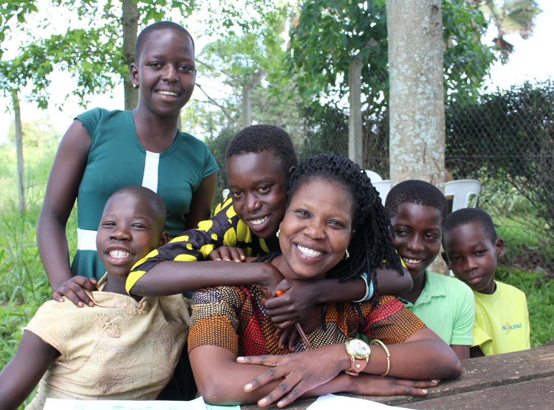 A teacher, Ms. Scovia, being hugged by a group of students