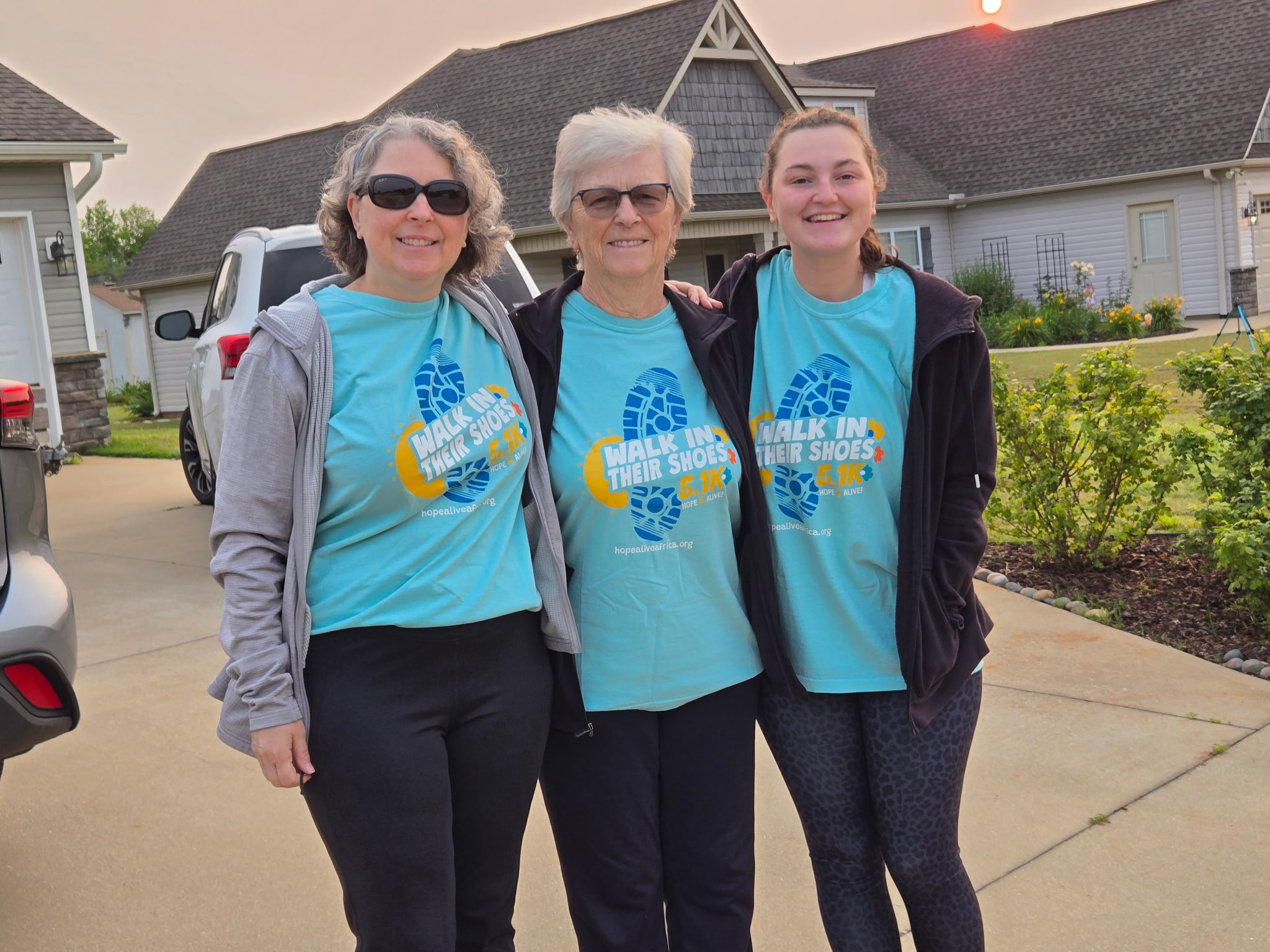 Grandmother mother and adult daughter in matching t-shirts in front of US home