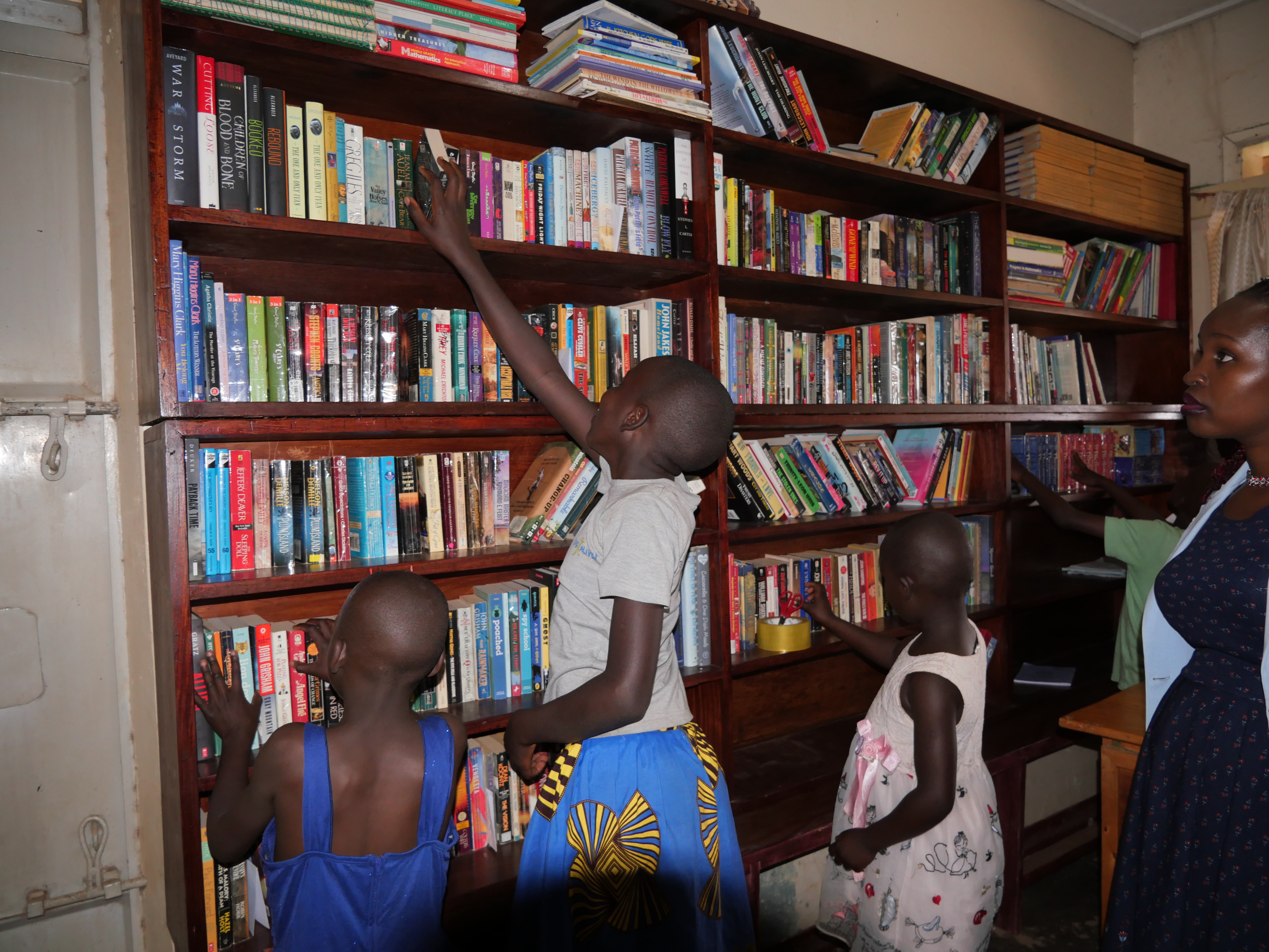 Child stretching to get a book from a tall shelf in a library