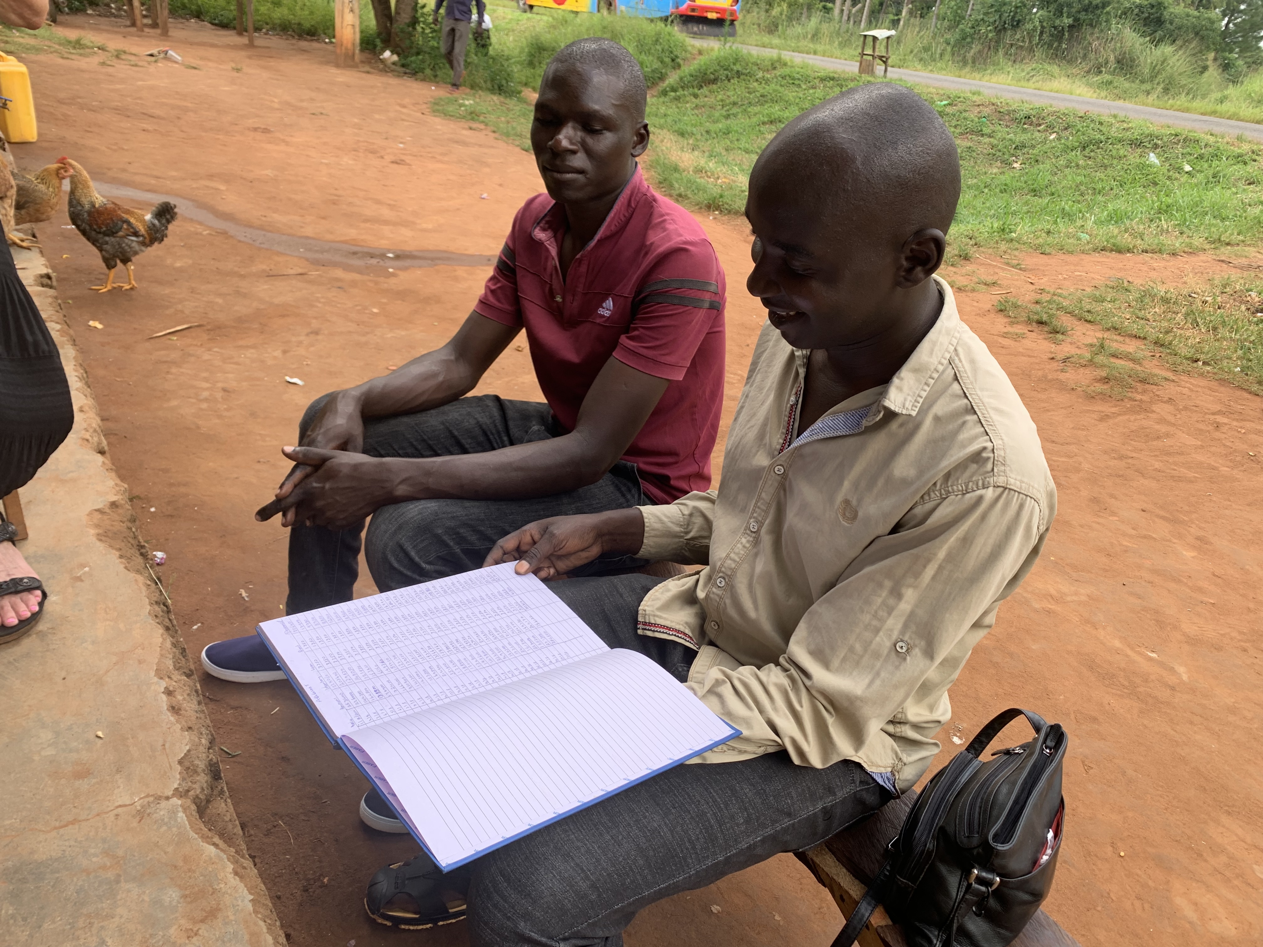 Two young men on a farm, looking at a ledger