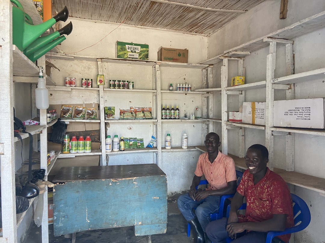Two seated men in a shop, smiling