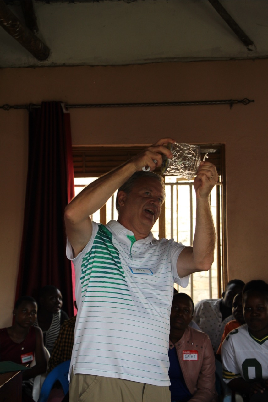 American man teaching students, holding up an object