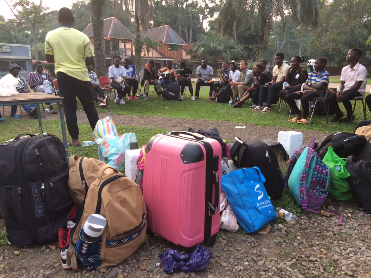 Arriving at camp Group of suitcases and backpacks with students in background