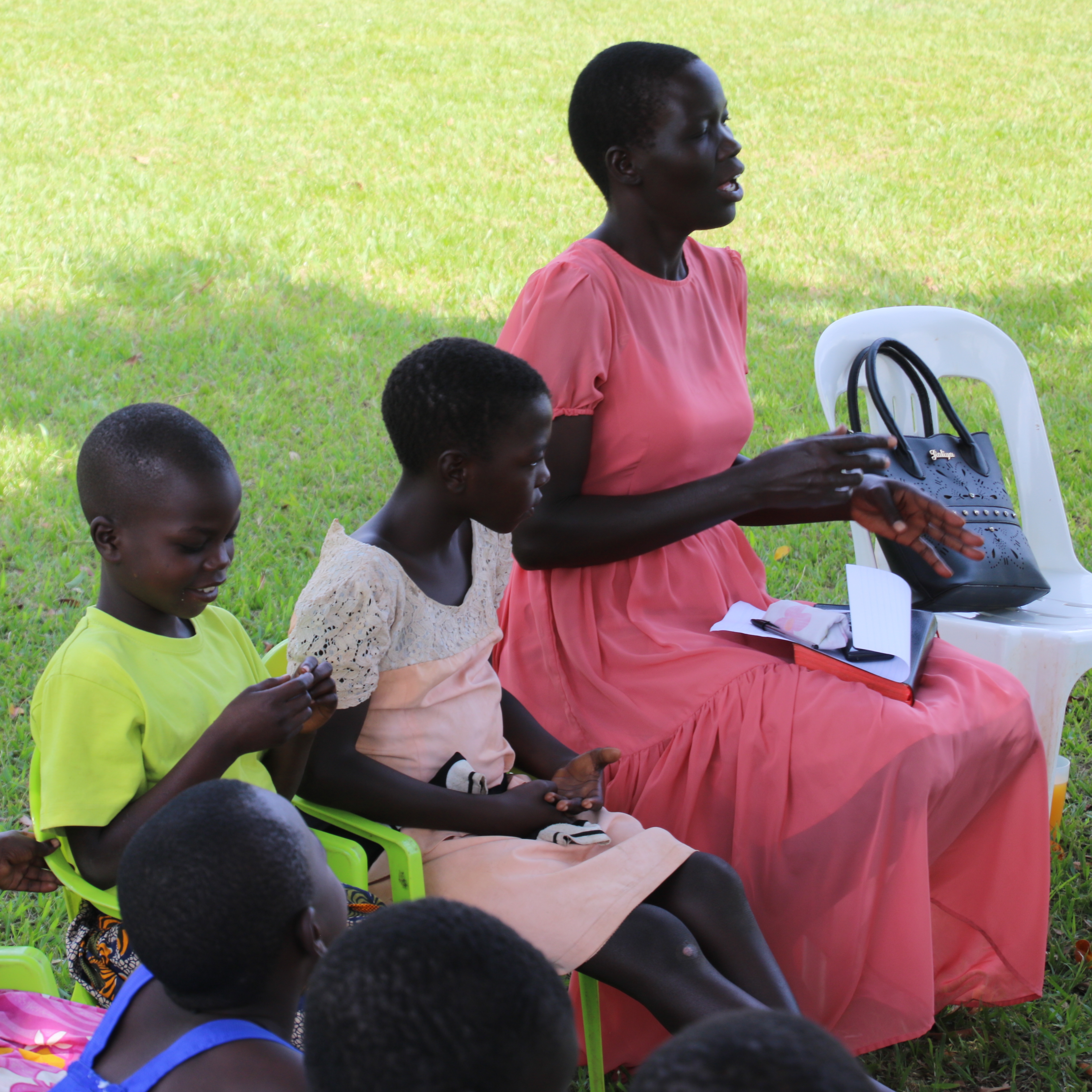 Woman sitting on grass with children singing